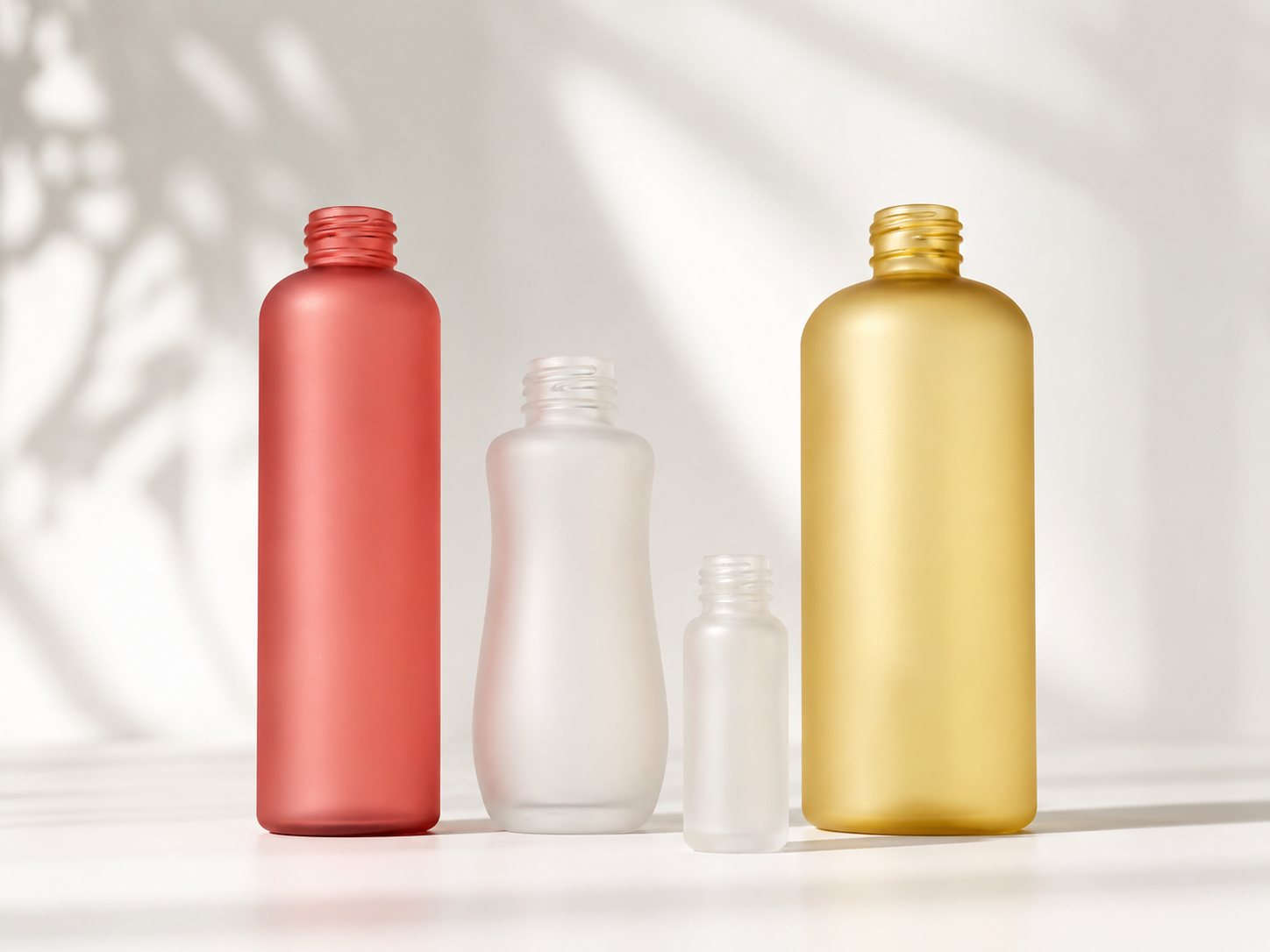 Trio de frascos foscos em vermelho, branco e dourado